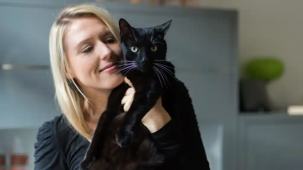 blonde woman cuddling black cat