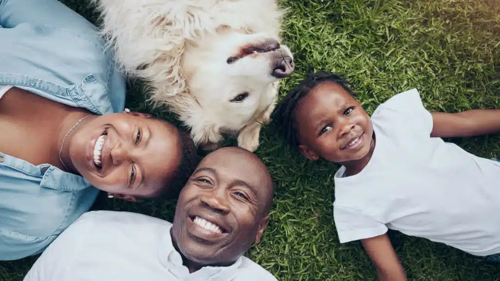 family lying on the grass with dog