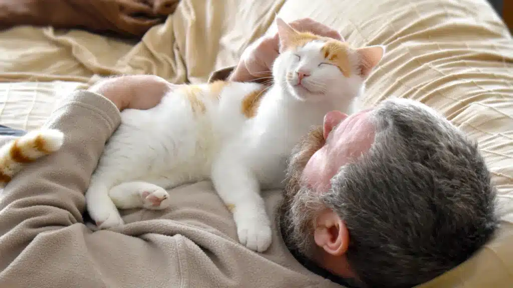 man cuddling cat on chest